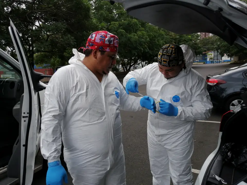 Paramédicos con equipo de bioseguridad junto a la unidad