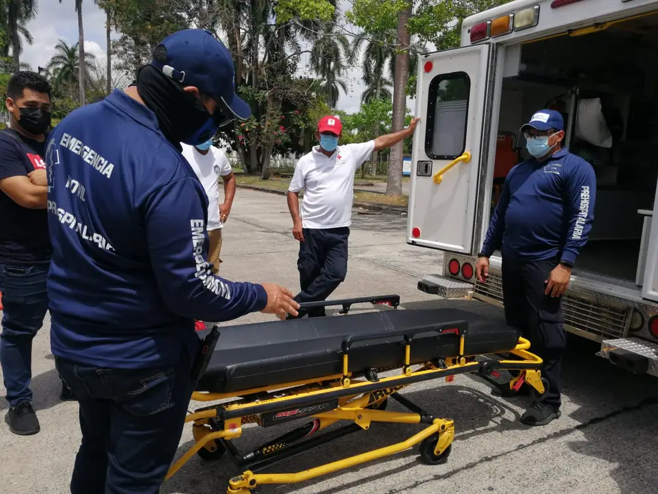 Paramédicos de Emergencia Móvil cargando una camilla en la ambulancia en Ciudad de Panamá